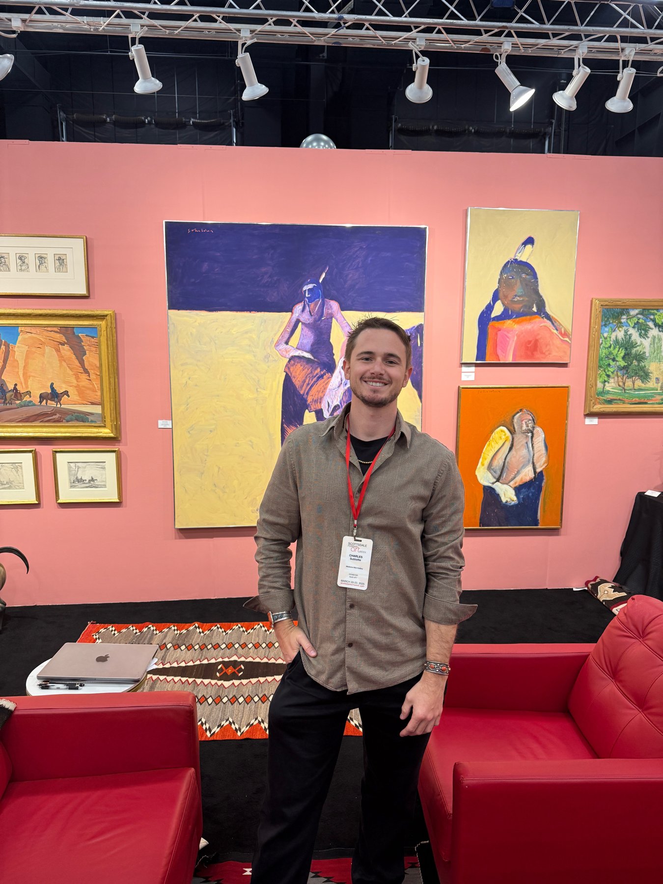 Charles Sublette at an art fair, surrounded by paintings